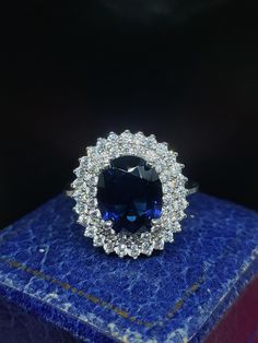 a blue and white diamond ring sitting on top of a blue box