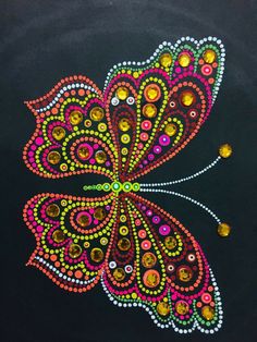 a colorful butterfly made out of beads on a black surface with yellow and pink dots