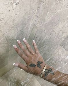 a woman's hand with tattoos on her left arm and wrist, in the rain