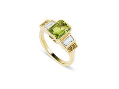 a yellow gold ring with two square cut diamonds and an emerald green stone in the center