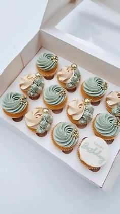 twelve cupcakes in a white box with frosting and decorations on the top