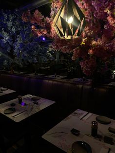 a dimly lit restaurant with flowers hanging from the ceiling