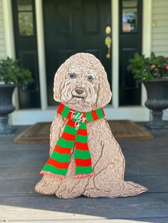 a statue of a dog with a scarf on it's neck sitting in front of a house