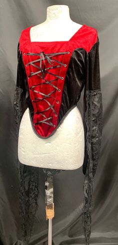 Rare find. This is an original Raven gothic black / Red corset top top . It has princess fiona sleeves fitted with finger ring and draped outer lace part , please refer to photos . The dummy the photo it taken on is a size 10 so I would say this top is a size 12/14 It does have stretch as it has Lycra side panels and a zip in the back Deadstock It is new with tags. Thank you for looking. Gothic Style Cosplay Top For Fall, Fitted Gothic Tops, Black Vampire Corset For Costume Party, Gothic Corset For Costume Party In Fall, Gothic Top For Costume Party In Fall, Gothic Long Sleeve Tops For Costume Party, Gothic Tops For Costume Party In Fall, Black Fitted Corset For Cosplay, Halloween Red Corset With Boned Bodice