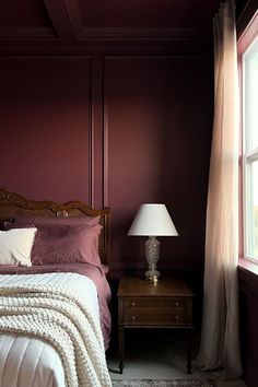 a bed sitting next to a window with a blanket on top of it in a bedroom