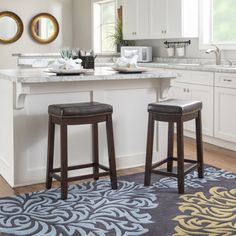 two stools in front of a kitchen island with an area rug on the floor