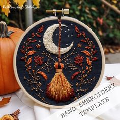 an embroidery project with pumpkins, leaves and a crescent on the table next to it