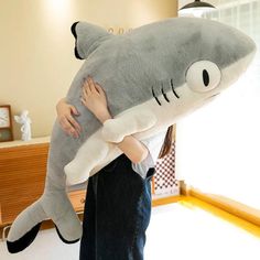 a woman holding a large stuffed shark in her arms and hugging it's face