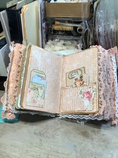 an open book sitting on top of a wooden table next to boxes and other items