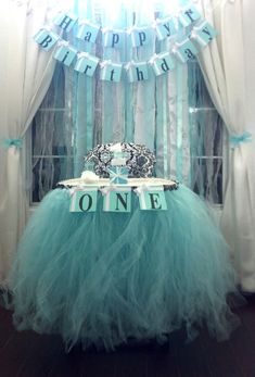 a table with a tiara on it in front of a birthday banner and curtains