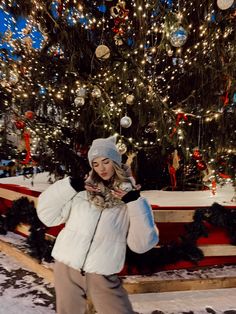 a woman standing in front of a christmas tree