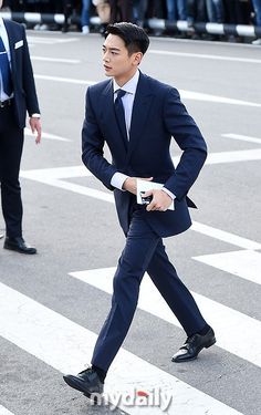 a man in a suit walking across a street