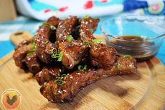 some meat is on a wooden plate with dipping sauce