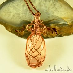 a copper wire wrapped pendant sitting on top of a rock