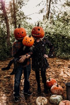 two people with pumpkins on their heads standing next to each other in the woods