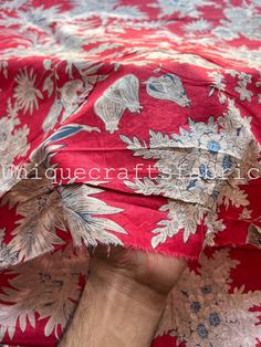 a person is hiding under a red and white floral print blanket with their hand on the edge