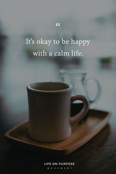 a coffee cup sitting on top of a wooden tray next to a glass jar with the words, it's okay to be happy with a calm life