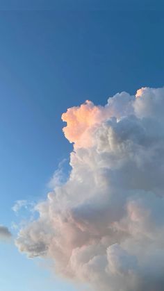 an airplane is flying in the sky with some clouds above it that are pink and blue