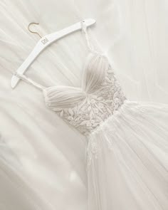 a white wedding dress hanging on a hanger