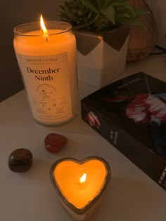 a candle that is sitting on a table next to some rocks and a box with a heart