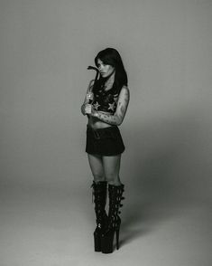 a black and white photo of a woman with tattoos on her arm holding a pipe