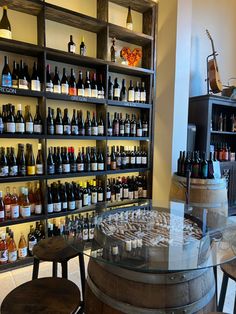 a wine cellar filled with lots of bottles next to wooden stools and shelves on the wall