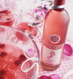 a glass bowl filled with ice and strawberries next to a bottle of pink wine