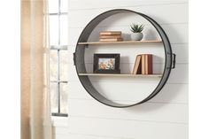 a round metal shelf with books on it and a potted plant in the corner