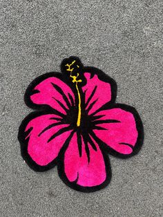 a pink flower is on the ground next to a black and yellow sticker that says hilo