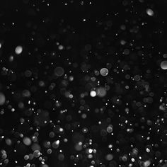 black and white photo of rain drops on the window glass in the dark night time