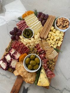 an assortment of cheeses, crackers and olives on a board