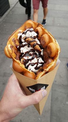 a person holding up a waffle filled with chocolate and marshmallow toppings