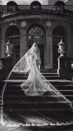 a woman in a wedding dress standing on some steps with her veil blowing in the wind