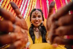 a woman in a yellow dress is smiling and making the peace sign with her hands