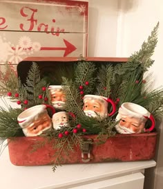 an old suitcase filled with christmas ornaments and greenery on top of a dresser next to a sign