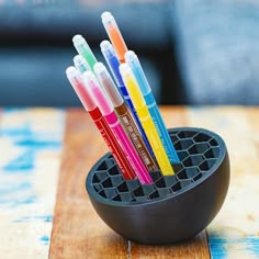 four pens in a holder on top of a wooden table