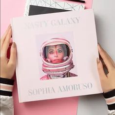 a person holding up a book with an image of a woman in space on it