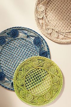 three decorative plates are sitting on a white table top, one is green and the other is blue