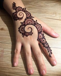 a hand that has a henna on it with flowers and swirls in the middle