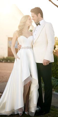 a man and woman in formal wear standing next to each other on the grass outside