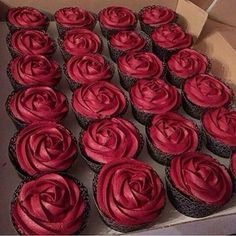 a box filled with red cupcakes sitting on top of a table next to each other