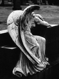 an angel statue sitting on top of a bench next to a grass covered park area