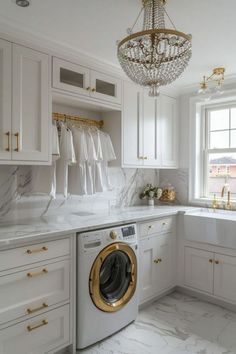 a washer and dryer in a white kitchen with gold accents on the cabinets