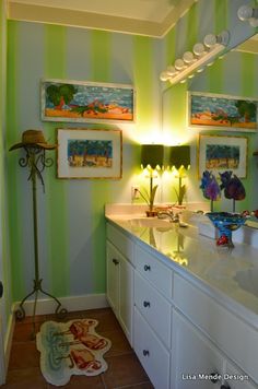 a bathroom with green and white stripes on the walls, two pictures above the sink