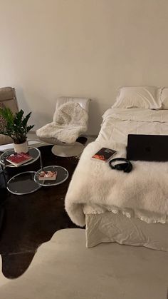 a bed sitting next to a table with a laptop on top of it