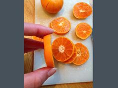 someone is peeling an orange on a cutting board with their thumbnails in the foreground