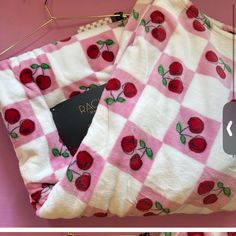 two pictures of the same blanket with cherries on it, one is pink and white