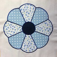 a blue and white flower with polka dots in the center on a piece of cloth