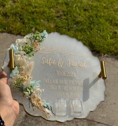 a person holding up a plaque with flowers on it