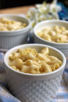 three white bowls filled with macaroni and cheese on a blue checkered cloth